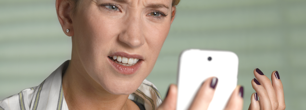 Women with a disgusted look on her face looks at cell phone after the call did not go through.